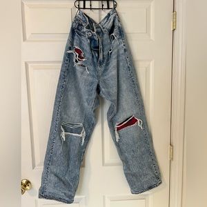 Ripped women’s AE mom jeans with black and red plaid pocket detail